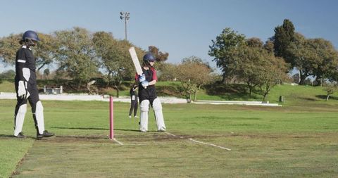 Female Cricket Players Practicing Batting and Teamwork Outdoors