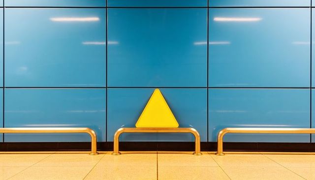 Yellow triangle accent centered on blue wall with stainless rails minimalist transit station