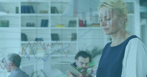 Businesswoman Analyzing Financial Charts on Tablet with Transparent Data Overlay in Office