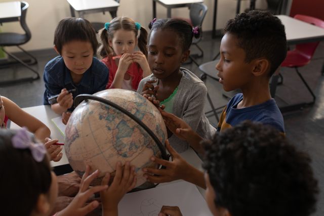 Group of kids studying a globe together in classroom of elementary school