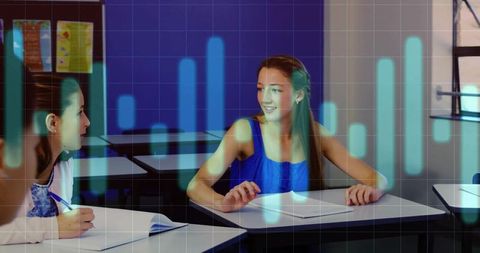 Smiling female student collaborating at desk with blue data visualization overlay