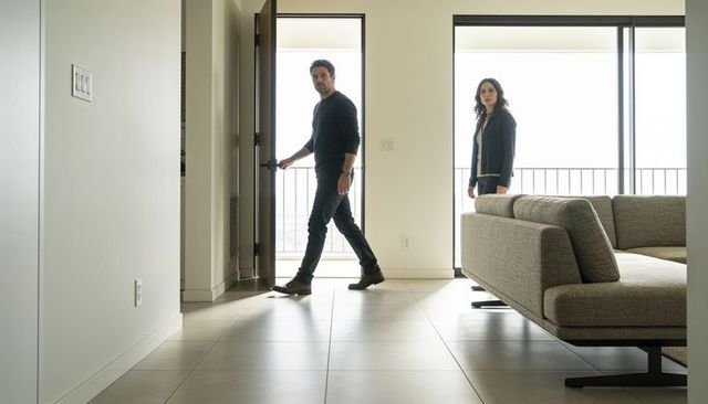 Couple entering modern minimalist apartment walking across tiled floor with wristwatch