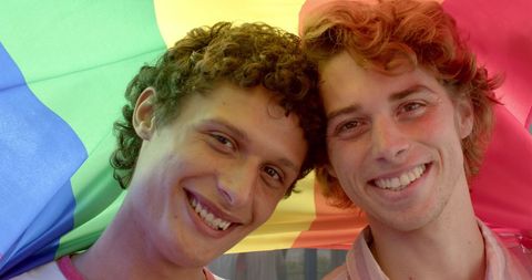 Joyful Young Gay Couple Celebrating Under Rainbow Flag