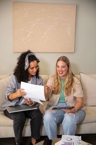 Women Colleagues Reviewing Document on Sofa In Serious Discussion