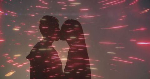 Silhouetted couple kissing with vibrant light streak effects