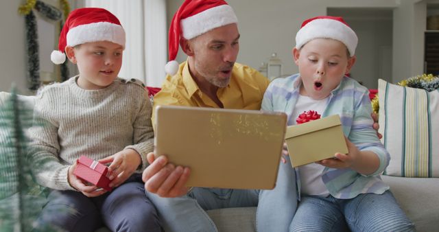 Excited family opening Christmas gifts wearing Santa hats on couch - Download Free Stock Images Pikwizard.com