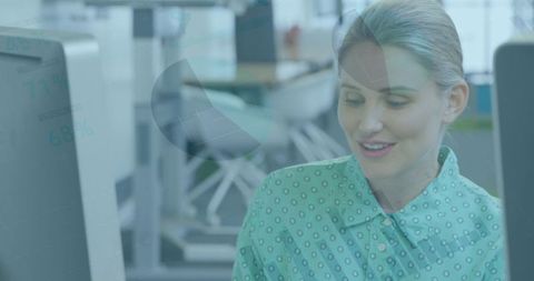 Smiling businesswoman working in modern office with data overlay