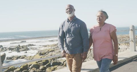 Happy Senior Couple Strolling Along Scenic Seaside Promenade