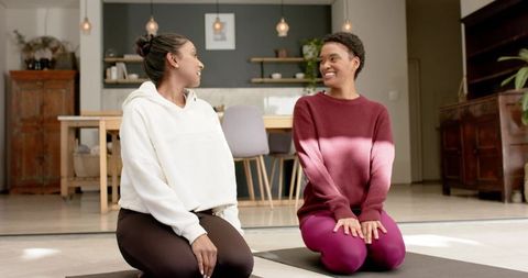 Diverse Female Friends Chatting on Yoga Mats in Modern Living Room