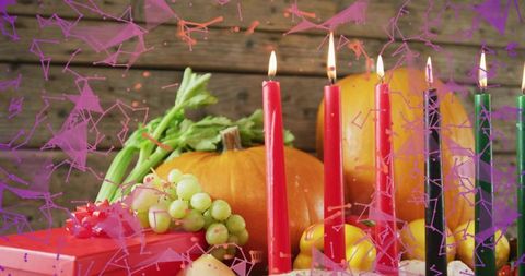 Kwanzaa-style harvest centerpiece with lit kinara candles, pumpkins, grapes and gift box