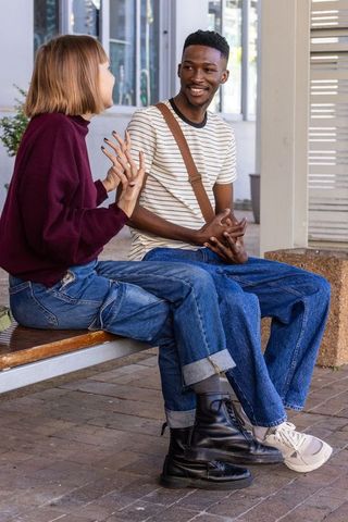 Campus friends chatting on bench outdoors casual conversation and friendly gestures