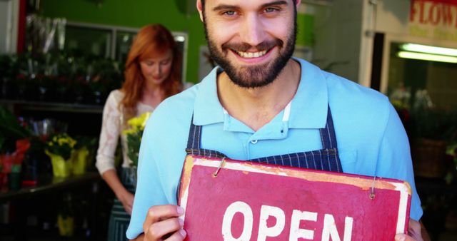 Smiling Florist Holding Open Sign at Flower Shop - Download Free Stock Images Pikwizard.com