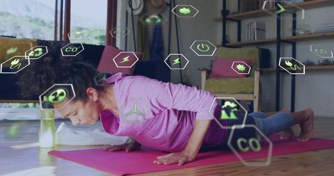 Woman doing push-ups at home with augmented reality fitness icons, yoga mat and water bottle