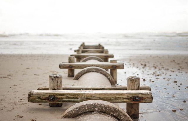 Weathered wooden bridge structures lead into the distance toward the ocean horizon. Ideal for themes of coastal nature, tranquility, rustic aesthetics, and exploring perspectives.