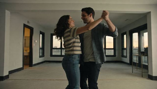 Young couple dancing in empty industrial loft at sunset showing intimacy and new home joy