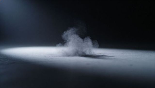 Hovering dust puff drifting across textured floor under dramatic spotlight