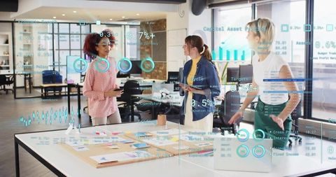 Women collaborating around table with AR analytics overlays, laptop and brainstorming notes