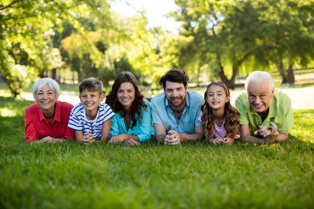 Multigenerational family lying on grass in park, enjoying sunny day. Grandparents, parents, and children smiling and bonding. Perfect for use in family-oriented advertisements, lifestyle blogs, and promotional materials for parks or outdoor activities.