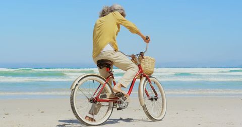 Elder Woman Riding Bicycle on Peaceful Beachfront - Download Free Stock Images Pikwizard.com