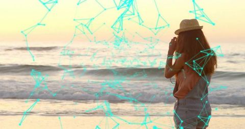 Woman Photographing Sunset at Beach with Digital Network Overlay