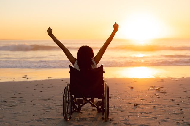 Rear view of disabled woman with arms up on the beach