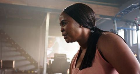 Determined african american woman leaning forward sweating after intense gym workout set