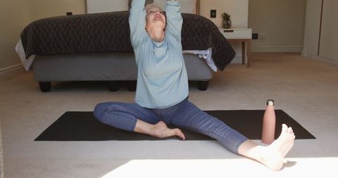Senior Woman Stretching on Yoga Mat in Cozy Bedroom Setting