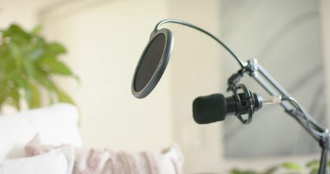 Recording podcast microphone on adjustable boom arm with pop filter in cozy living room