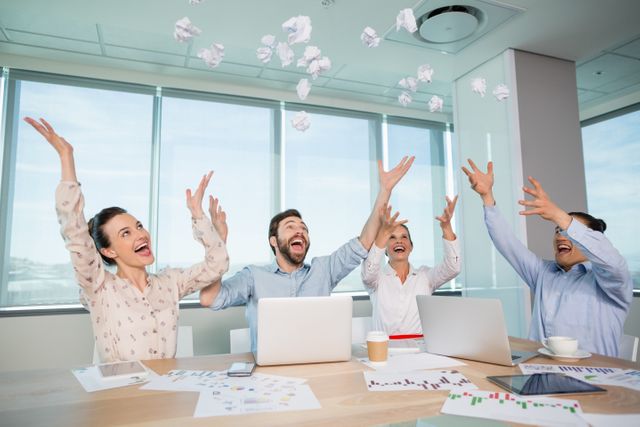 Business executives celebrating success by throwing crumpled paper in the air. Ideal for depicting teamwork, office celebrations, professional achievements, and a positive work environment. Can be used in articles, blogs, and presentations about workplace culture, team building, and corporate success.