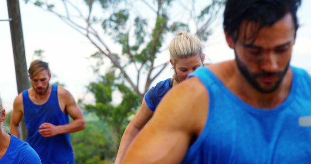 Group of individuals working out together outdoors, wearing blue athletic clothing. Ideal for use in articles, blogs, and promotional materials related to fitness, teamwork, outdoor activities, healthy living, activewear promotions, and lifestyle enhancement programs.