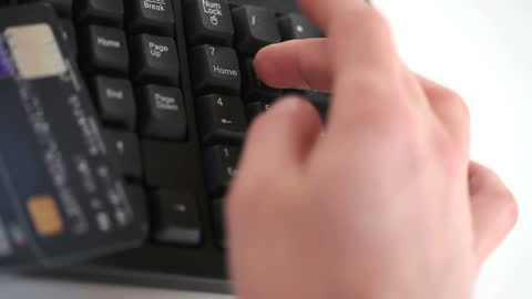 Person Typing on Keyboard with Credit Card for Online Shopping