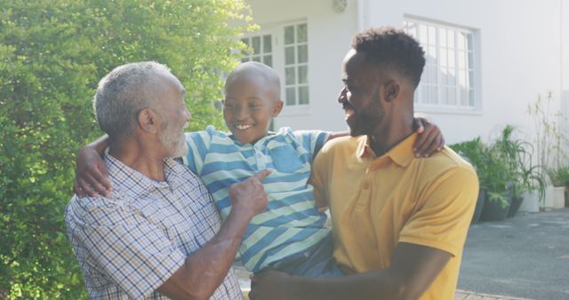 Happy african american grandfather, father and son embracing and smiling in garden. Lifestyle, domestic life, family, and togetherness.