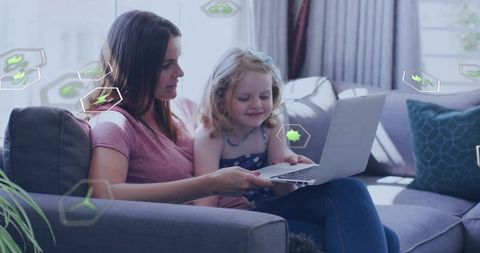 Mother and daughter sharing laptop on couch, learning and bonding with digital overlays
