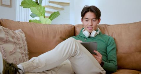 Relaxed Individual Using Tablet on Sofa with Headphones in Cozy Living Room