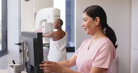 Female Mammography Tech Operating Console While African American Woman Receiving Mammogram