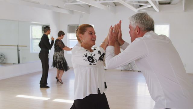 Caucasian senior couples actively participating in a ballroom dancing class, expressing joy and enthusiasm. Ideal for use in promotions for senior fitness programs, dance classes, health and wellness activities for the elderly, social activity marketing, and retirement community advertising.