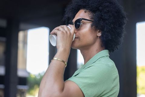 African american man sipping coffee outdoors wearing sunglasses green shirt gold bracelet