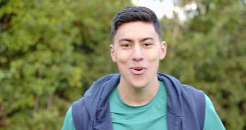 Energetic Young Man in Garden with Green Shirt and Blue Vest