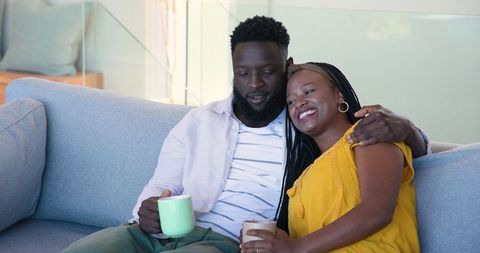 Couple Relaxing on Couch with Coffee, Sharing Joyful Moment