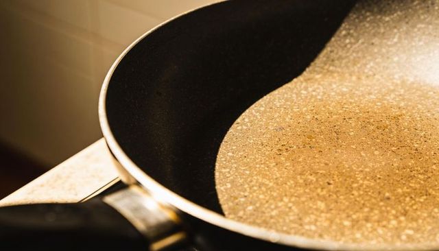 Speckled nonstick frying pan sitting on stove in warm light closeup kitchen cookware