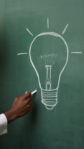 Hand sketching lightbulb on chalkboard in vertical video, showcasing creativity and innovation