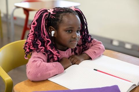 Focused Young Student Listening While Writing in Class