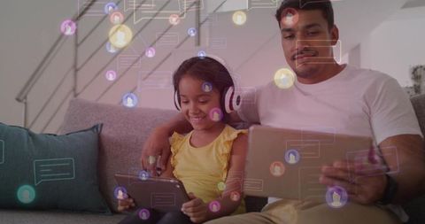 Father and Daughter Sharing Tablets on Couch, Enjoying Online Learning and Messaging