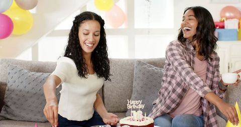 Two Women Celebrating Birthday with Cake and Balloons in Living Room