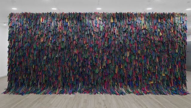 Floor-to-Ceiling Multicolor Fabric Tapestry with Dense Vertical Fringe and Spotlights