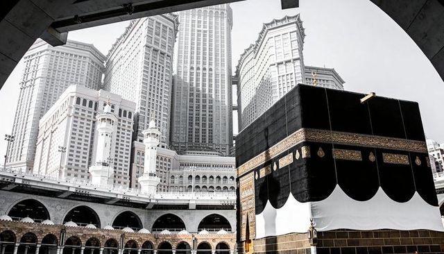 Kiswah-covered kaaba dominating masjid al-haram courtyard with gold bands and minarets
