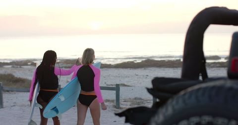 Two Surfers Headed to Early Morning Waves Holding Surfboards
