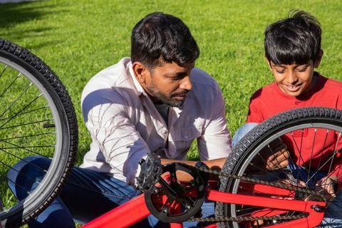 Father and son assembling bicycle indoors on bright lawn