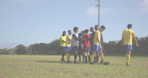 Youth soccer players shaking hands after match on sunny community field