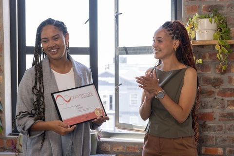 Two Diverse Female Coworkers Celebrating Achievement in Office